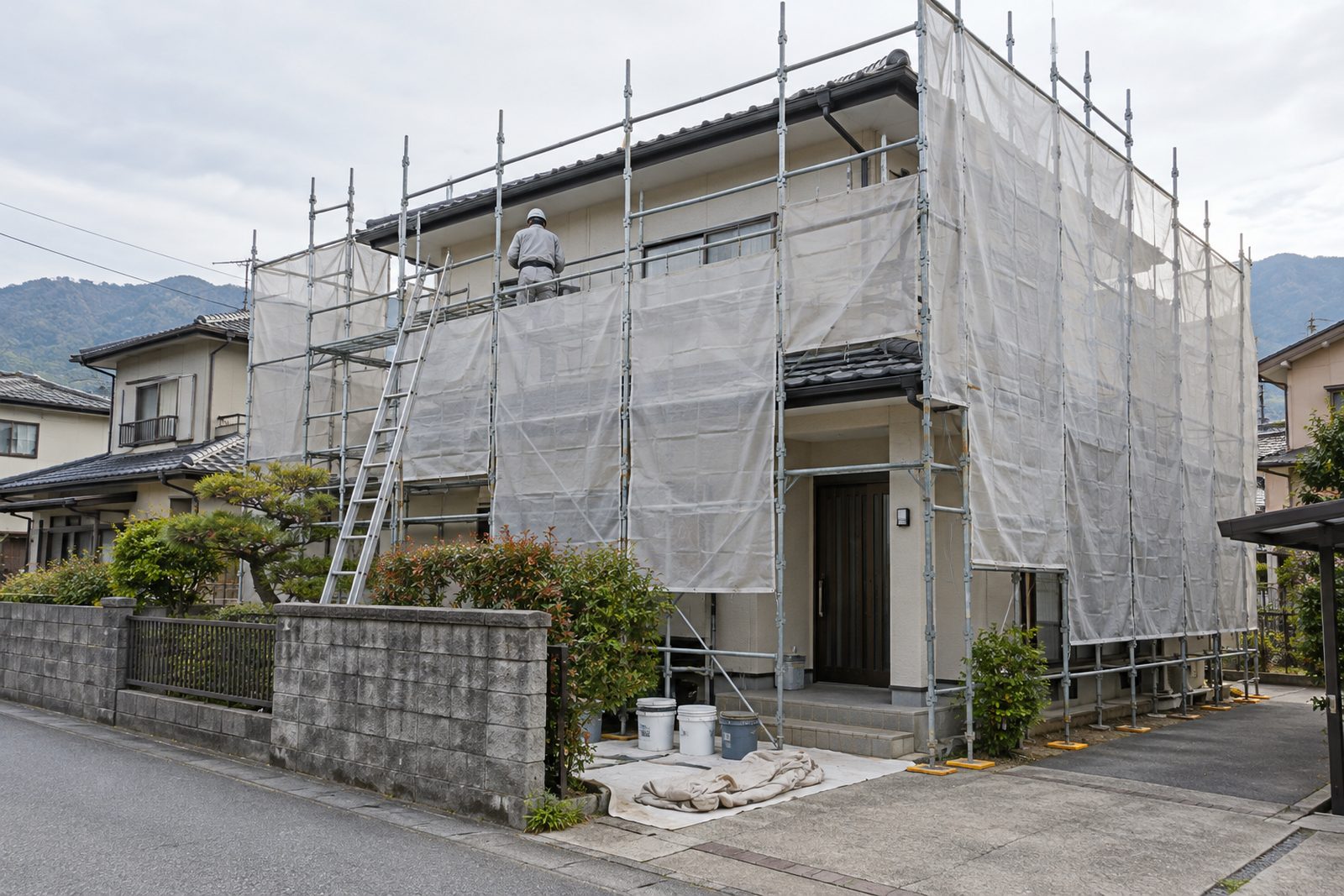足場とメッシュシートを掛けて外壁の塗り替えを進めている住宅のイメージ写真